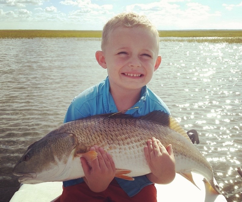 Picture of a young child holding a large tagged red drum.  