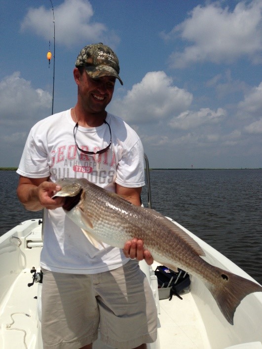 Picture of an adult man holding a large tagged red drum.