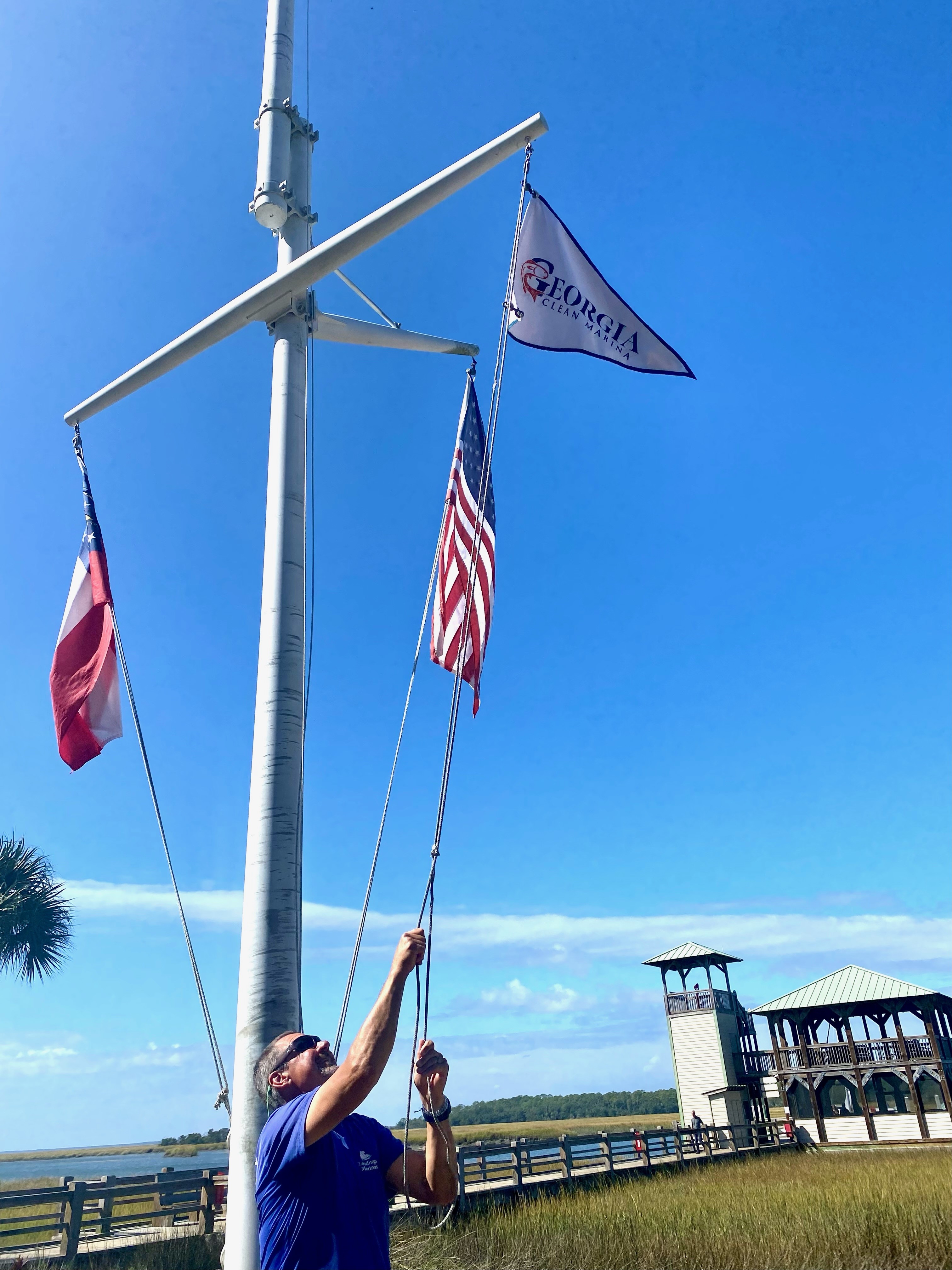 Michael Marino, Dockmaster at Delegal Creek Marina in the Landings, hoists their GA Clean Marina certification flag at their marina Oct. 25, 2023.  Photo by Bryan Fluech/UGA Marine Extension and Georgia Sea Grant