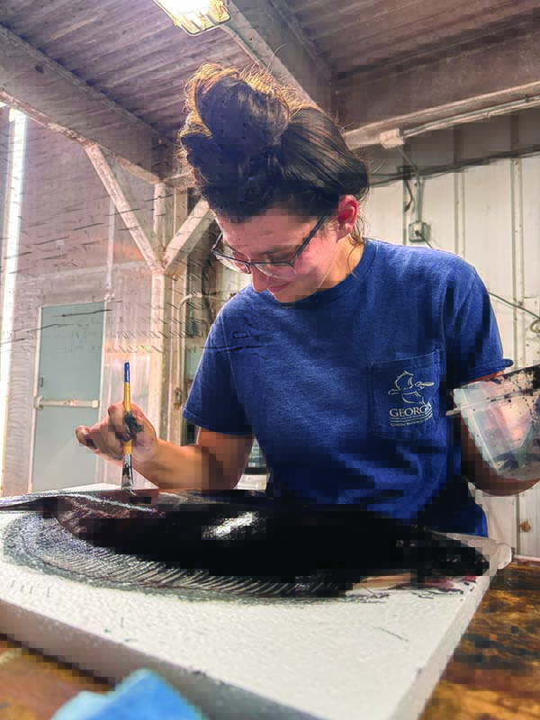 Britany Hall, a marine biologist with CRD, carefully spreads sumi ink onto a flounder before pressing muslin cloth onto the fish.