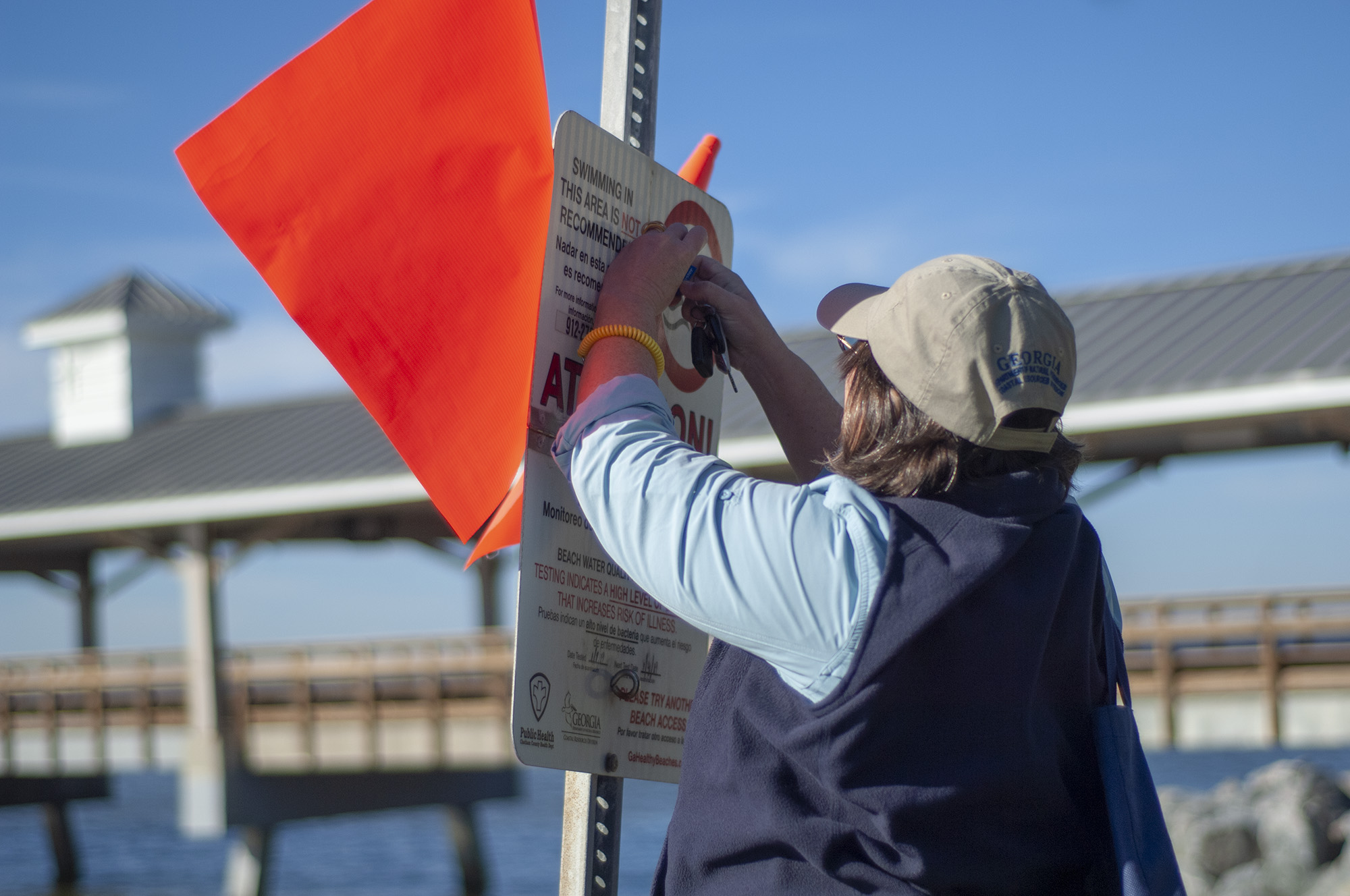 : Elizabeth Cheney, a beach water quality manager with the Coastal Resources Division of the Georgia Department of Natural Resources, tends to a beach advisory sign near Pier Village on St. Simons Island.