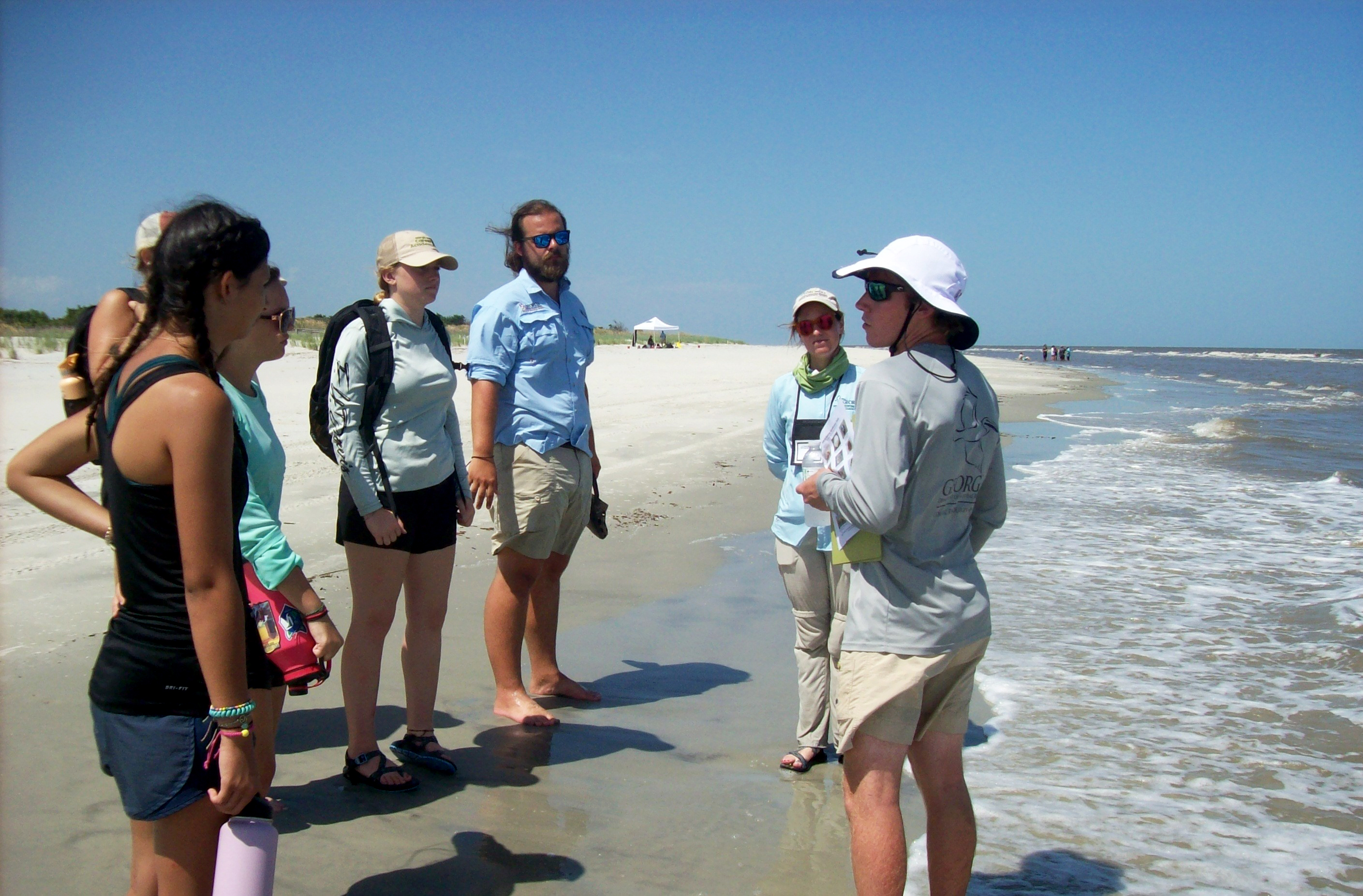 Hunter Jackson, far right, speaks with students from the 2022 DNR Career Academy on Jekyll Island as he leads a beach walk. 